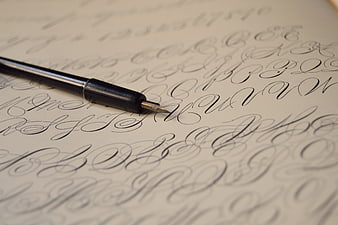 Close-up of calligraphy pen on vintage cursive handwriting