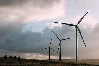 Wind turbines on a grassy hill under dramatic cloudy sky