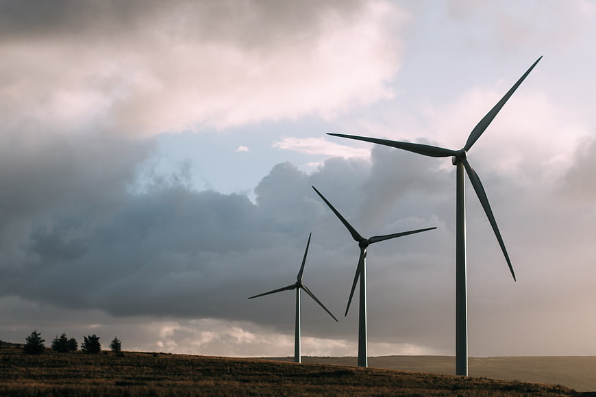 Wind turbines on a grassy hill under dramatic cloudy sky