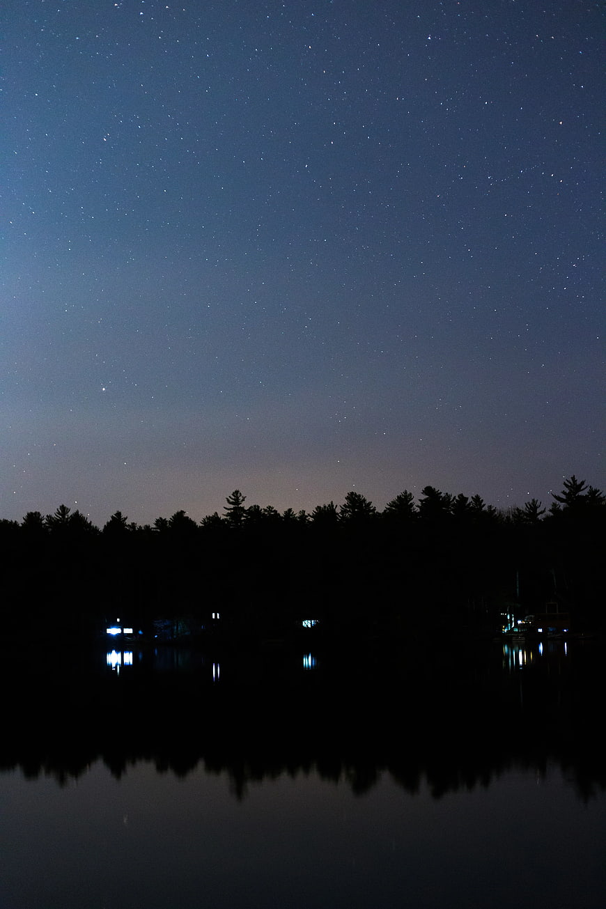 Starry Night Sky Over Lake With Tree Silhouettes