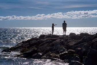 Couple Pointing at Ocean Horizon from Rocky Shore