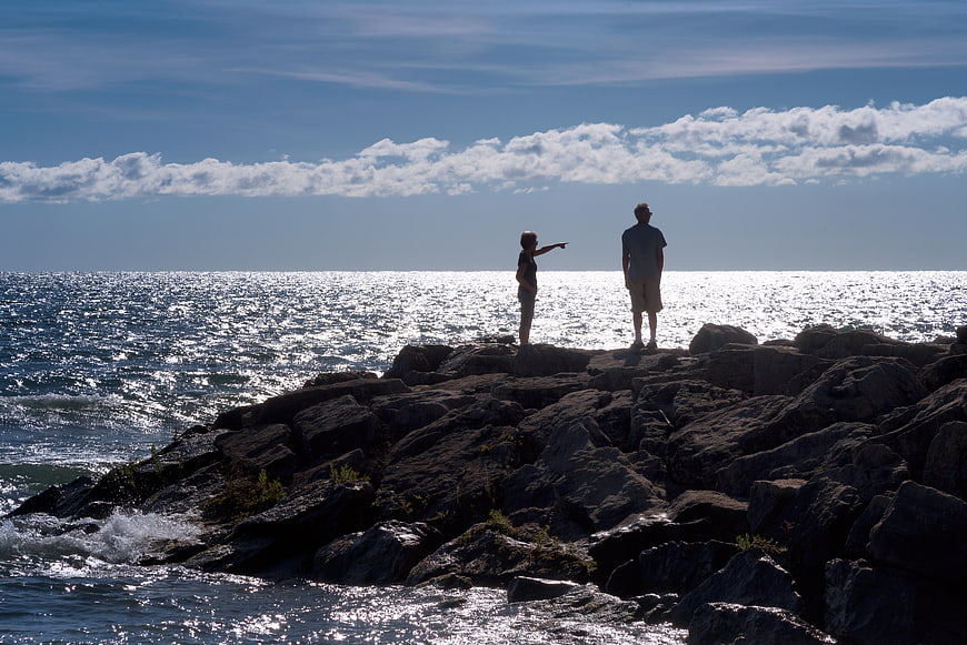 Couple Pointing at Ocean Horizon from Rocky Shore