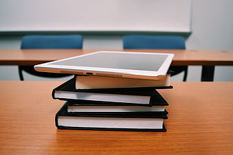 Tablet on Stack of Books in Classroom Setting