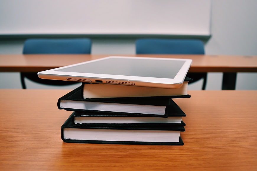 Tablet on Stack of Books in Classroom Setting