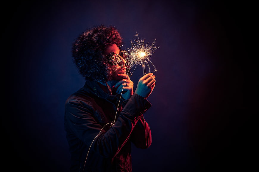 Man with afro holding sparkler in dark studio