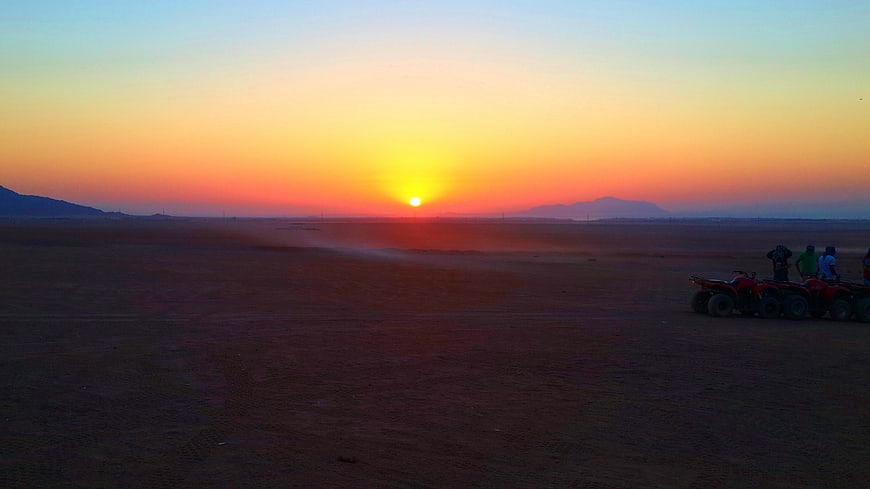 Desert sunset with ATVs and riders in foreground