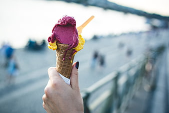 Hand holding colorful melting gelato cone outdoors
