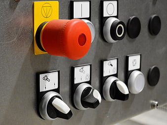 Close-up of industrial control panel with red emergency stop button