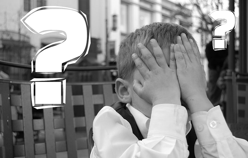 Boy covering face with hands and question marks