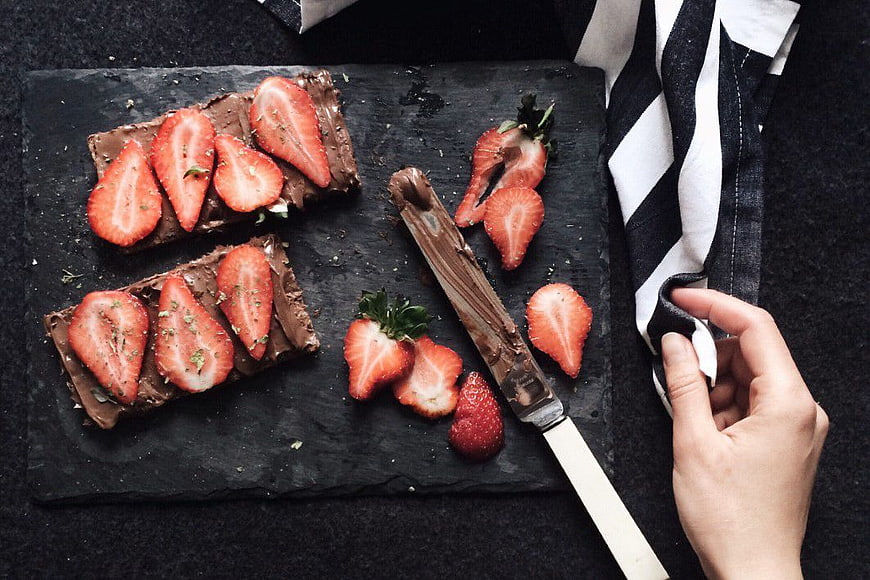 Flat lay of chocolate toast with sliced strawberries on slate