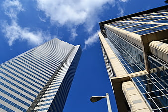 Low angle view of modern glass skyscrapers against a bright blue sky