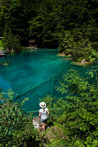 Woman in Hat Viewing Turquoise Lake with Submerged Trees