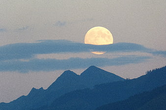 Full Moon Rising Over Mountain Peaks At Dusk