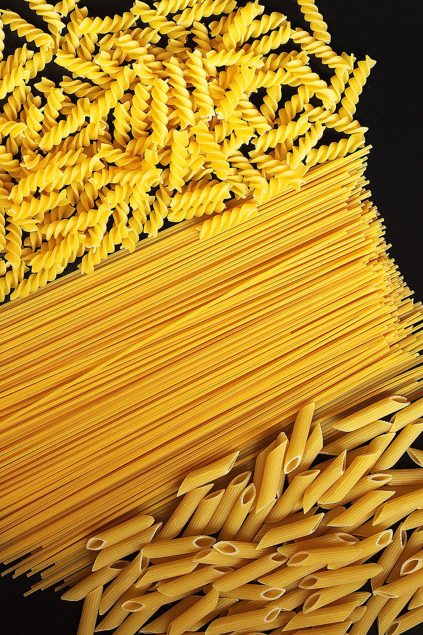 Assortment of Uncooked Pasta Shapes on Black Background