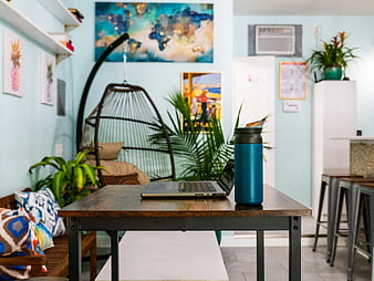 Laptop and Blue Tumbler on Wooden Table in Cozy Workspace