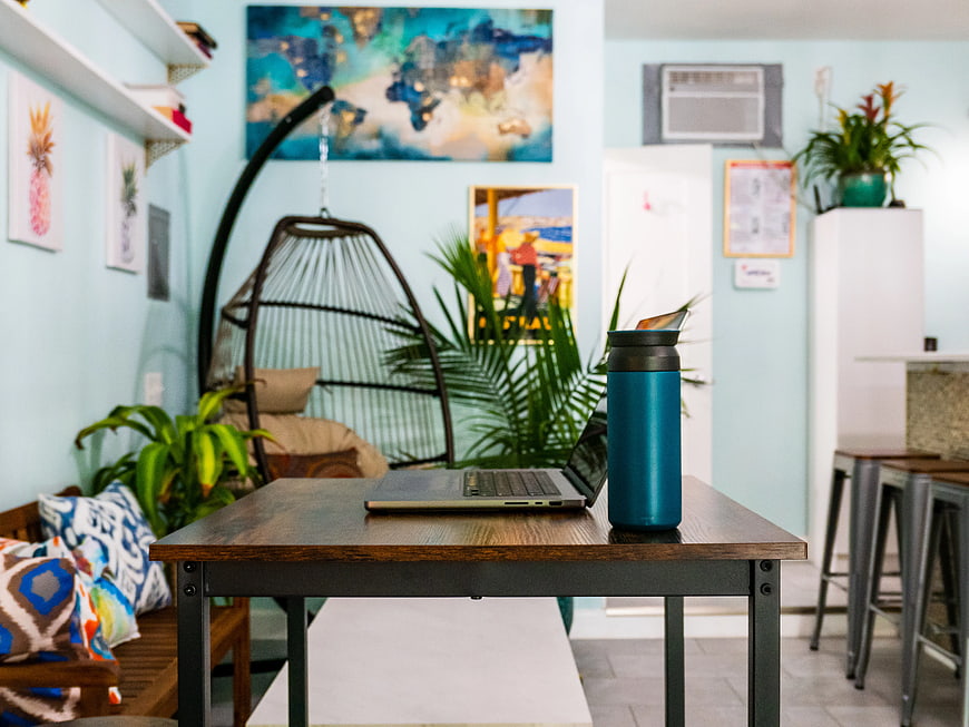 Laptop and Blue Tumbler on Wooden Table in Cozy Workspace