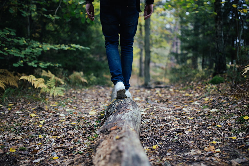 Man balancing on fallen log in autumn forest