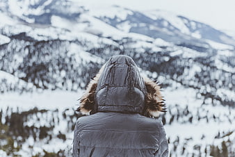 Person in Winter Jacket Looking at Snowy Mountains