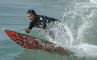 Surfer Riding Wave With Red Tribal Surfboard