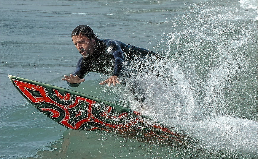 Surfer Riding Wave With Red Tribal Surfboard