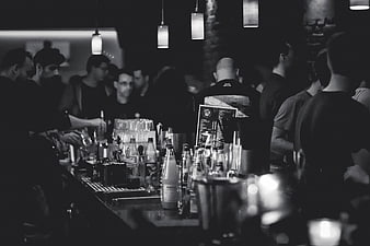 Black and white bar scene with bottles and crowd