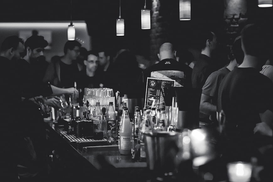 Black and white bar scene with bottles and crowd