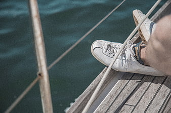 White sneakers on wooden boat deck with sea background