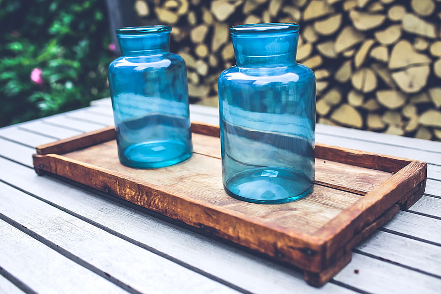 Two blue glass jars on rustic wooden tray outdoors