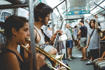 Musicians playing banjo and trumpet on a crowded subway train