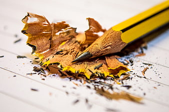 Close-up of yellow pencil with wood shavings on paper