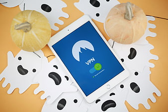 Tablet with VPN app surrounded by Halloween ghosts and pumpkins