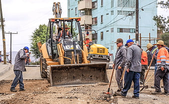 Construction workers and heavy machinery on an urban road repair site