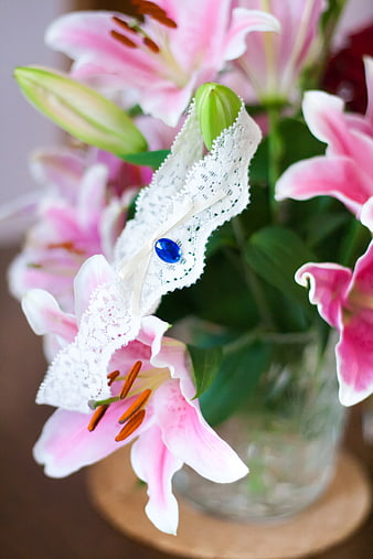 Pink lily bouquet with white lace wedding garter and blue gem