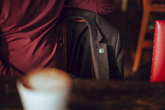 Close-up of grey blazer with camera pin in cafe