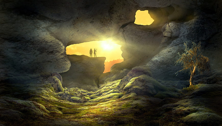 Silhouetted figures in a mystical cave looking at sunset