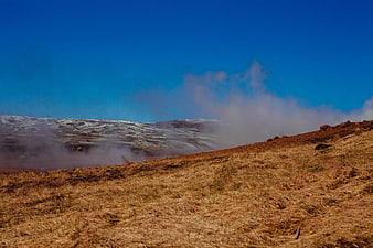 Misty Brown Grassy Hillside Under Blue Sky