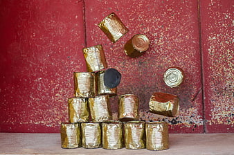 Gold tin cans falling in slow motion against red background