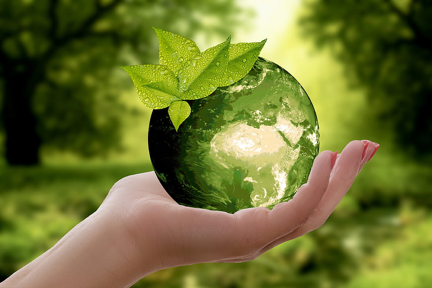 Hand holding green earth globe with leaf symbolizing sustainability