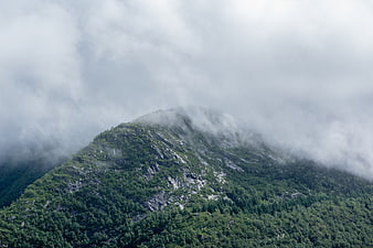 Misty Mountain Peak with Green Forest and Clouds