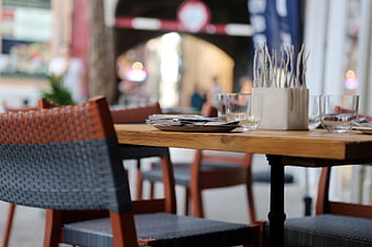 Outdoor Cafe Table Setting with Wooden Chairs and Blurred Background