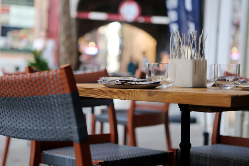 Outdoor Cafe Table Setting with Wooden Chairs and Blurred Background