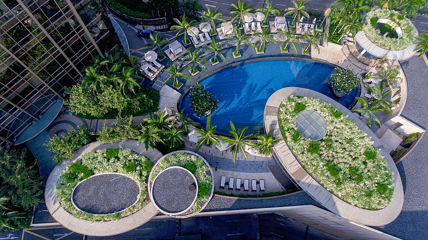 Aerial view of luxury hotel rooftop pool with tropical garden