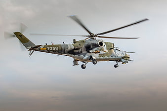 Military attack helicopter in flight against cloudy sky