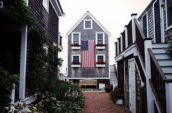 American Flag on Gray House in Cobblestone Alley