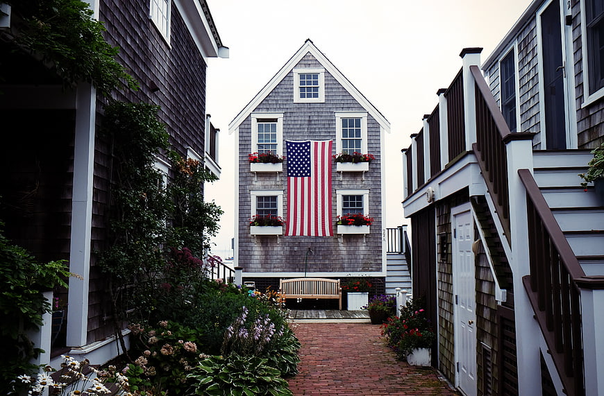 American Flag on Gray House in Cobblestone Alley
