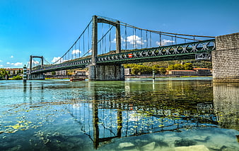 Suspension bridge over the Rhone river with clear water reflection