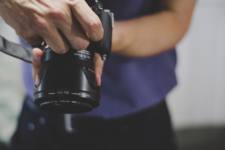 Close-up of hands holding a professional DSLR camera