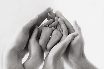 Black and white photo of adult hands holding baby feet