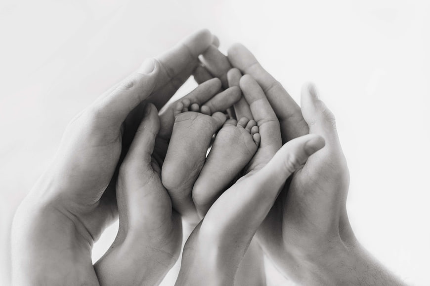 Black and white photo of adult hands holding baby feet