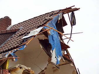 Damaged Residential House Roof With Exposed Insulation And Broken Tiles